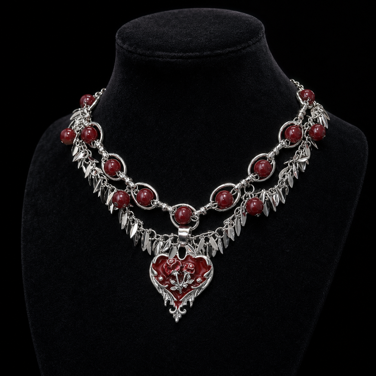 Layered gothic red heart necklace displayed on a black velvet jewelry bust